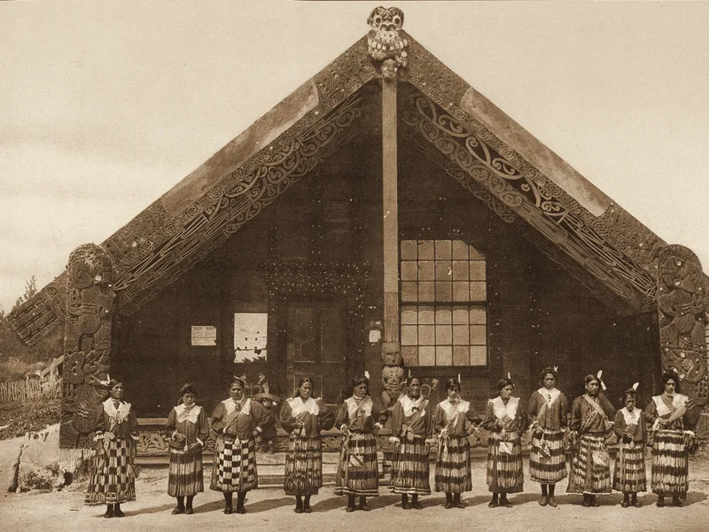 Poi performers at a carved meeting house, Ōhinemutu, 1890s. Public domain.